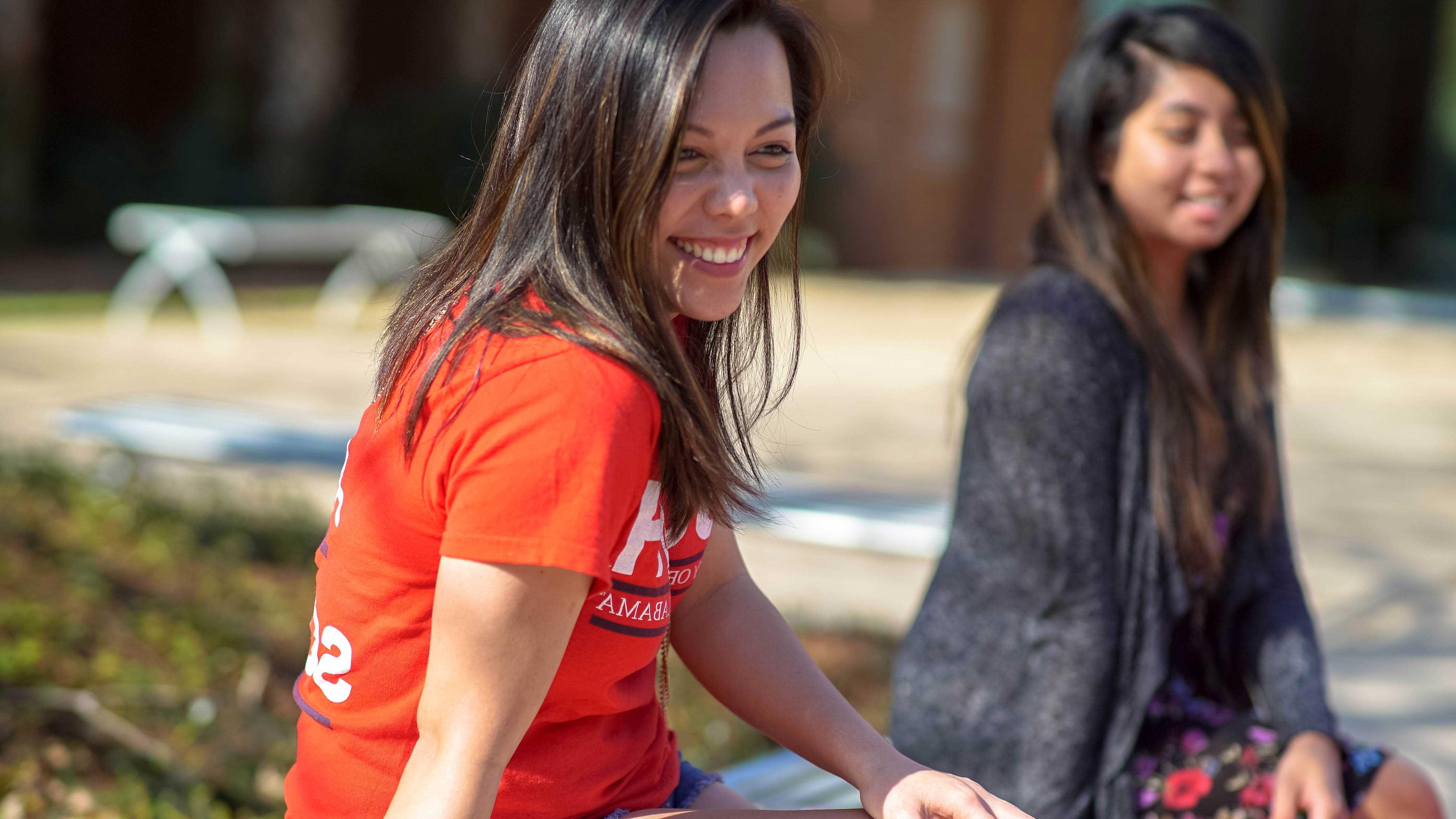 Two students sitting outside smiling